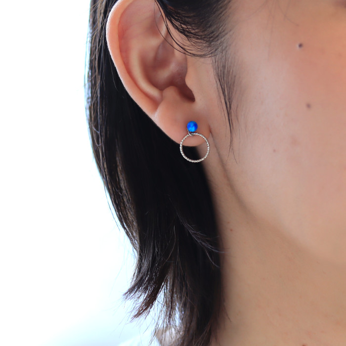 プラチナリングチャームと青色の京都オパールのピアスを耳に着けた女性の耳元画像