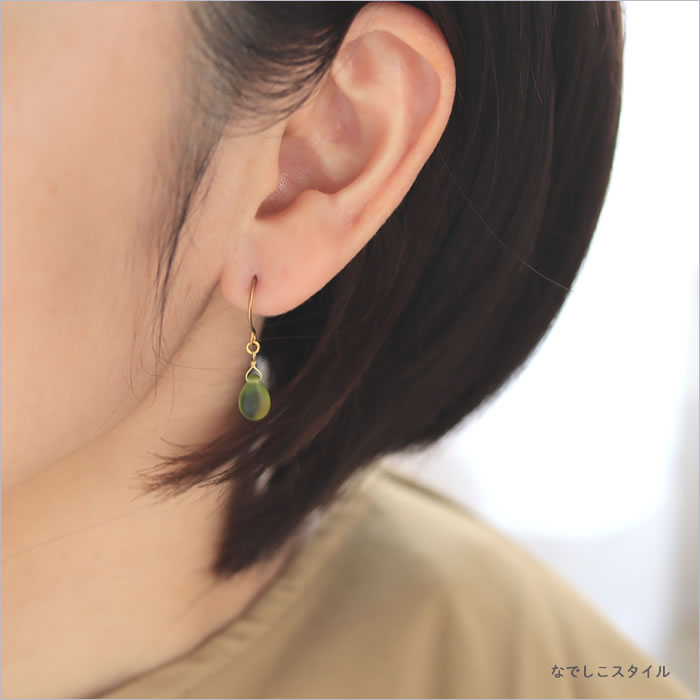 緑色のしずく型のピアスを耳に着けている４０代女性の横顔