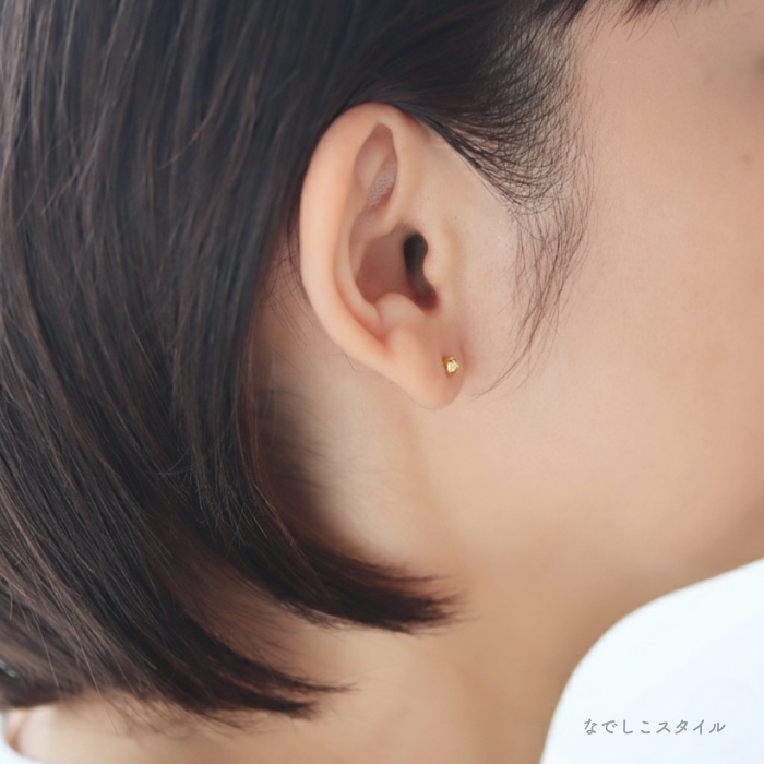 金属部分すべてがチタン純度99.5％の丸玉ピアスゴールドカラーを耳に着けた女性の横顔画像