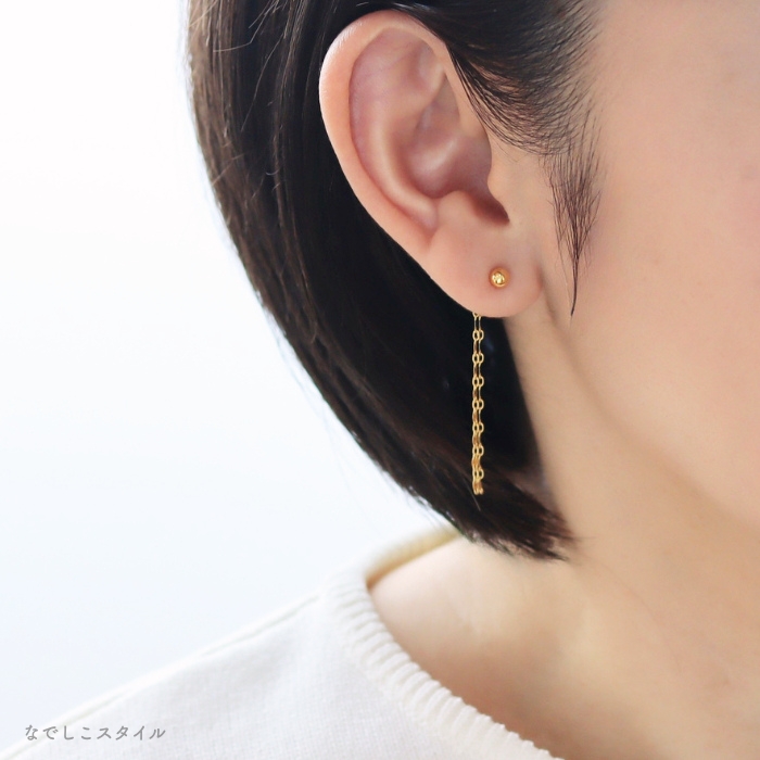 金属部分すべてがチタン純度99.5％の丸玉ピアスゴールドカラーとバックキャッチを耳に着けた女性のお出かけイメージ
