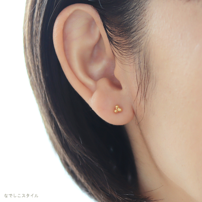 ゴールドカラーのキンモクセイの形のピアスをつけた女性の耳元画像