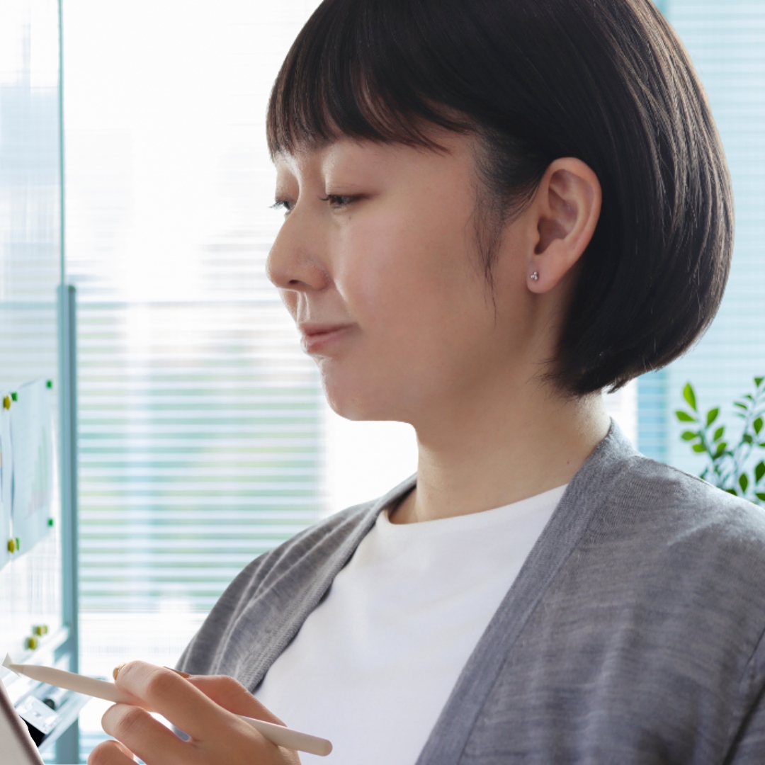 プラチナカラーのキンモクセイの形の純チタンピアスをつけて仕事をしている女性の耳元画像

