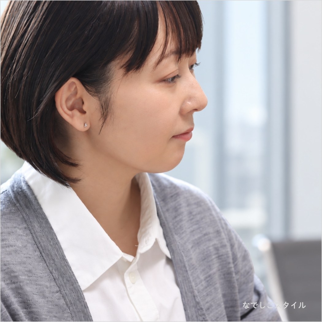 ゴールドカラーの金木犀の形の純チタンピアスをつけて仕事をしている女性の耳元画像