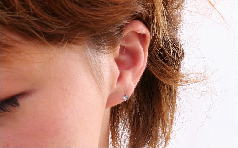 プラチナ軸のチタンピアス、CZスクエア「スカイブルー」の女性の耳につけている画像