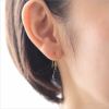 プラチナカラーの純チタンフック使用のティアドロップピアス「ジェットブラック」、女性の耳につけている画像