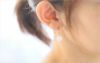純チタン使用の,四つ葉のクローバー「ローズクオーツ」を耳につけた女性の画像