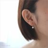 純チタン使用の、「ノワ/貝パールのゆれるスタッドピアス」を耳につけた女性の画像