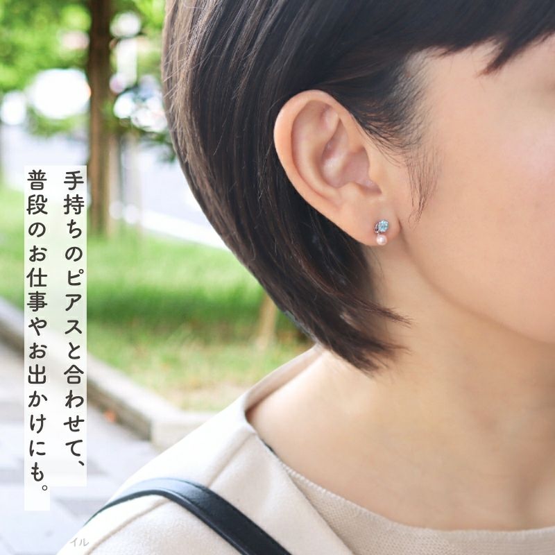 グリーンサファイアのピアスに桜色パールチャームをつけた女性の春の通勤イメージ画像