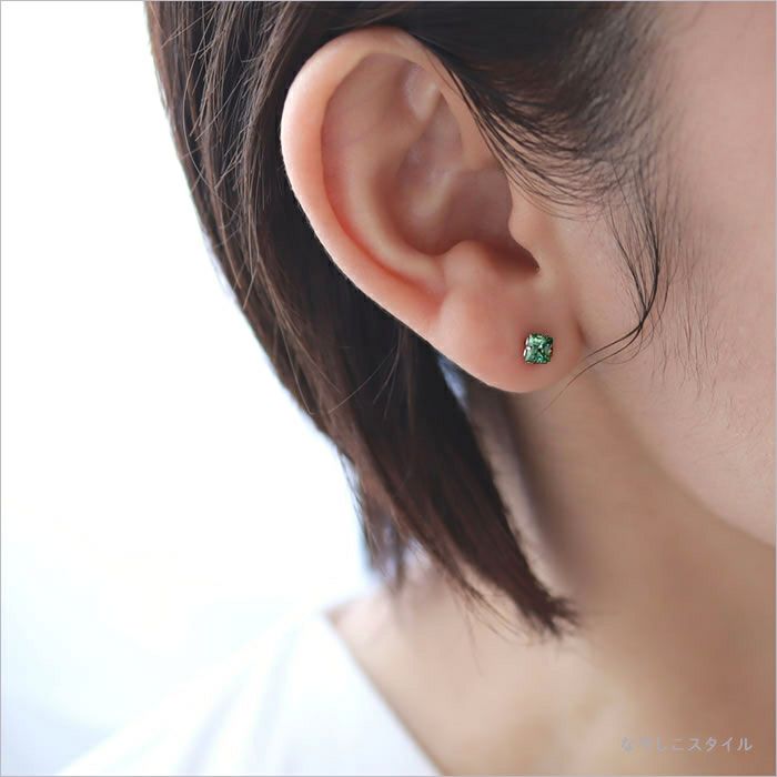 四角いサファイアグリーンのピアスと白いトップスのコーディネート画像