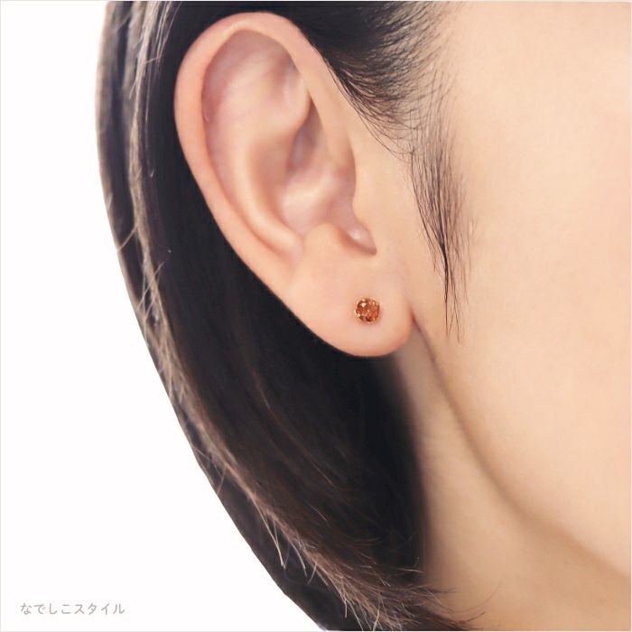 チタンピアスゴールドカラーブランデートパーズ４ｍｍを着けた女性の耳アップの画像