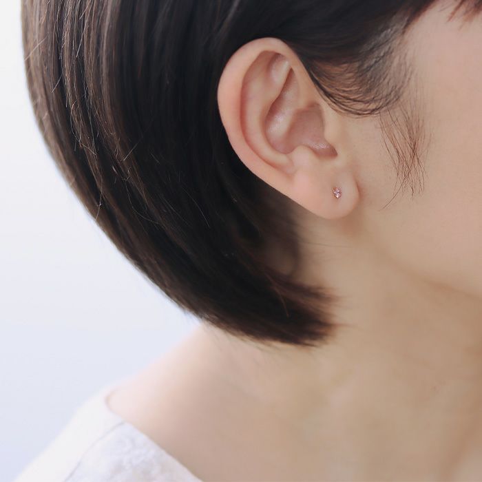 軸の色がゴールドカラーのサファイアピンク。ひし形のカルテット2.5mmを着けた40代女性の横顔